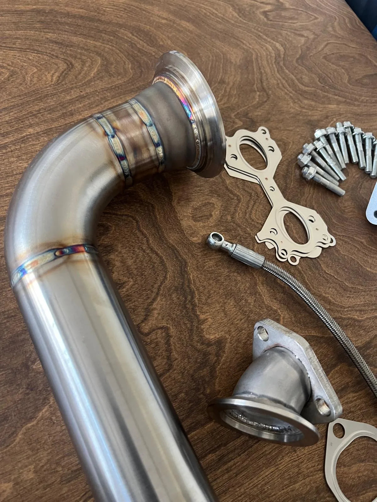 Metal exhaust pipe and related components on a wooden surface
